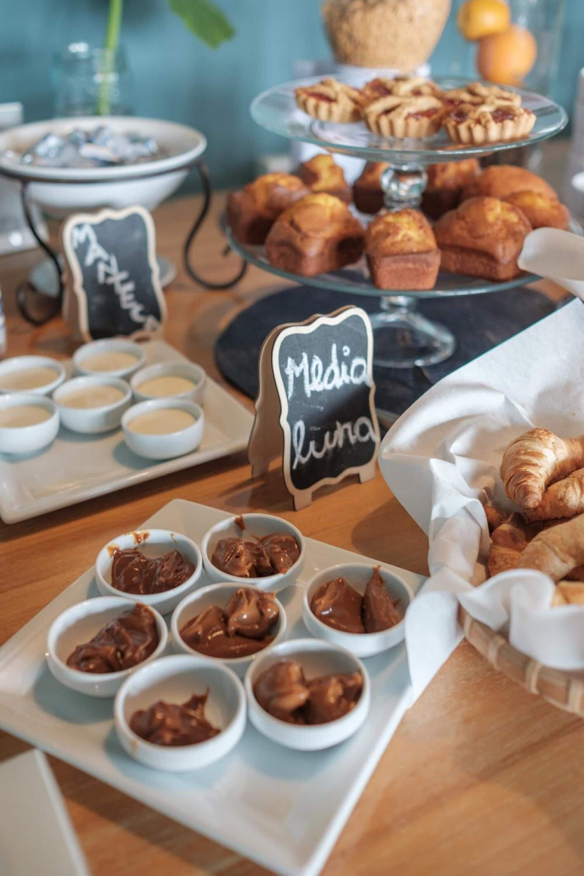 A buffet with various pastries, chocolate spreads, and a chalkboard sign reading "Media Luna."
