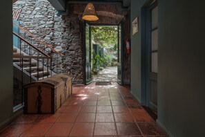 A hallway with a stone wall, a wooden bench, and a staircase.