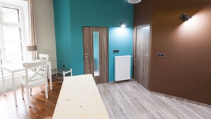 A room with teal walls, a wooden door, a white radiator, and a white table. - Fancy Ernesto II (Budapest)