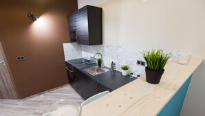 A modern kitchen with dark cabinets, a stainless steel sink, a wooden countertop, and two potted plants. - Fancy Ernesto II (Budapest)