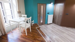 A room with a wooden floor, a white table with chairs, a teal wall, and two doors. - Fancy Ernesto II (Budapest)