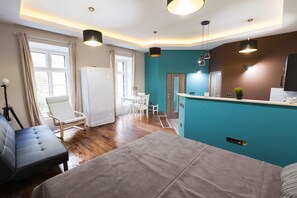 Relax in a spacious room with a large bed, sofa, and armchair, surrounded by a calming neutral color palette and a statement teal accent wall.