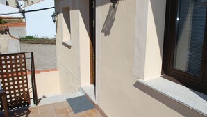 A building with a tiled entrance, a wooden gate, and a light fixture on the wall. - Apartamentos Rurales El Trillo (Malpartida de Plasencia)