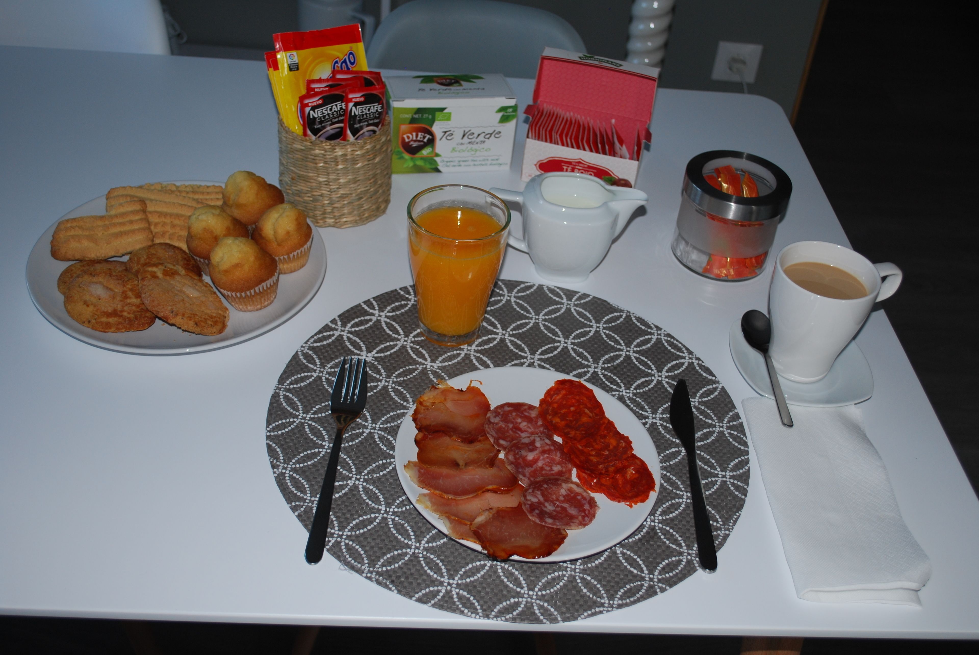 A breakfast table with pastries, juice, coffee, and condiments.