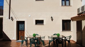 A patio with a table and chairs, a door, and a window. - Apartamentos Rurales El Trillo (Malpartida de Plasencia)
