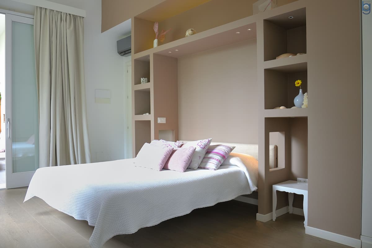 A bedroom with a bed, bedside tables, and built-in shelving.