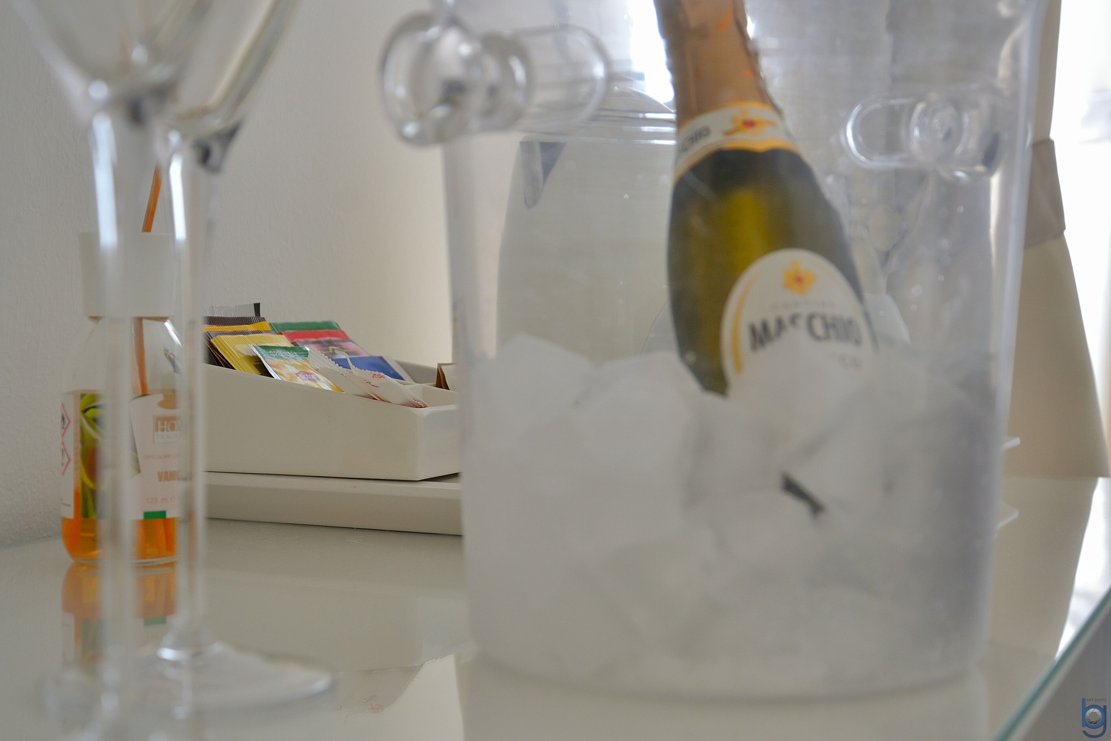 A bottle of Macchiato champagne in a glass container filled with ice cubes.