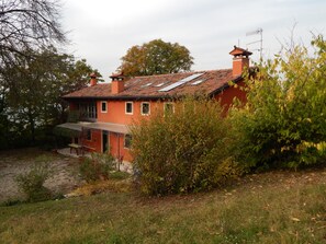 A red house with a tiled roof, a chimney, and a small porch.