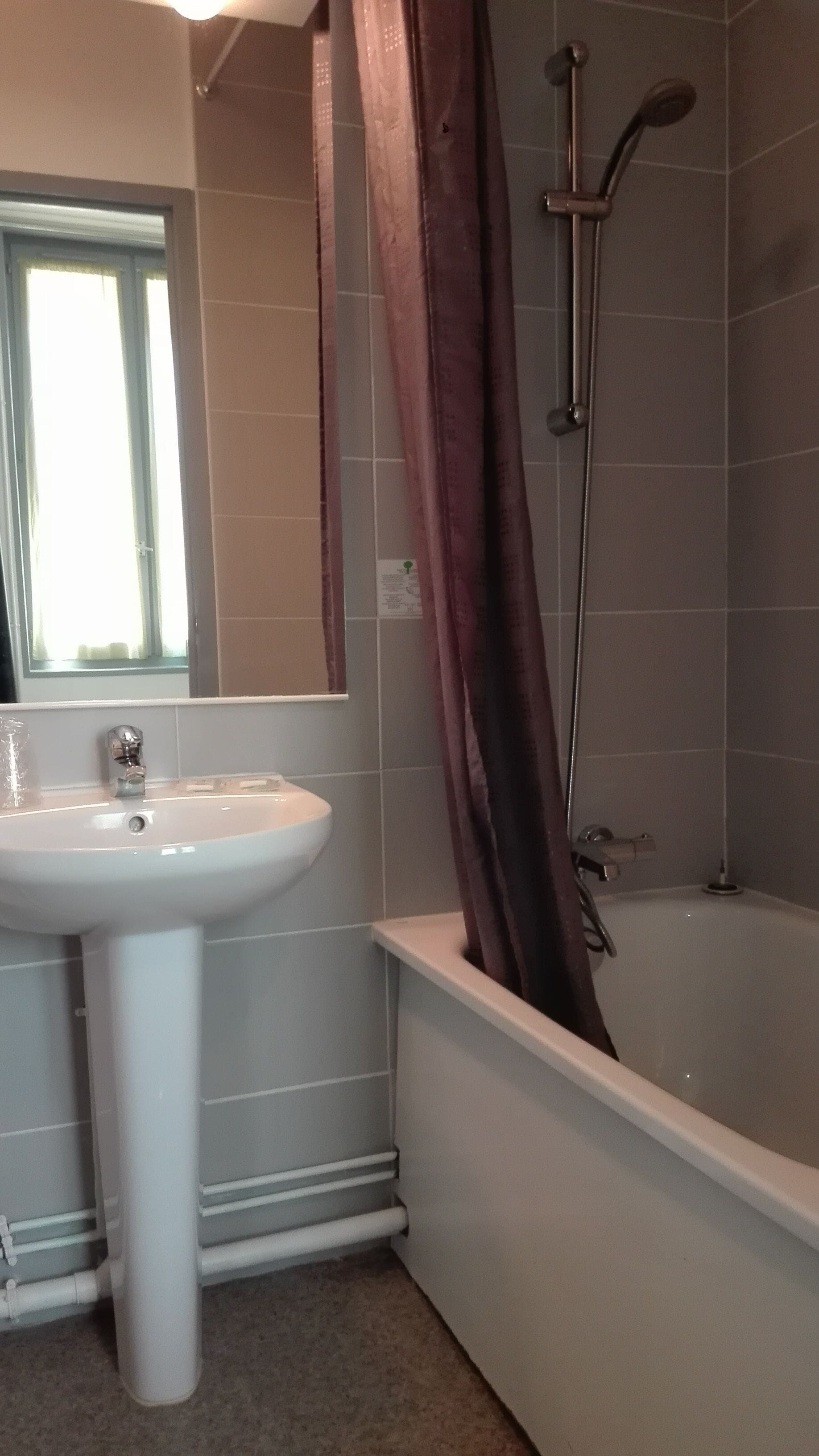 Un baño con lavamanos blanco, un espejo, ducha con cabezal de ducha manual y bañera.
