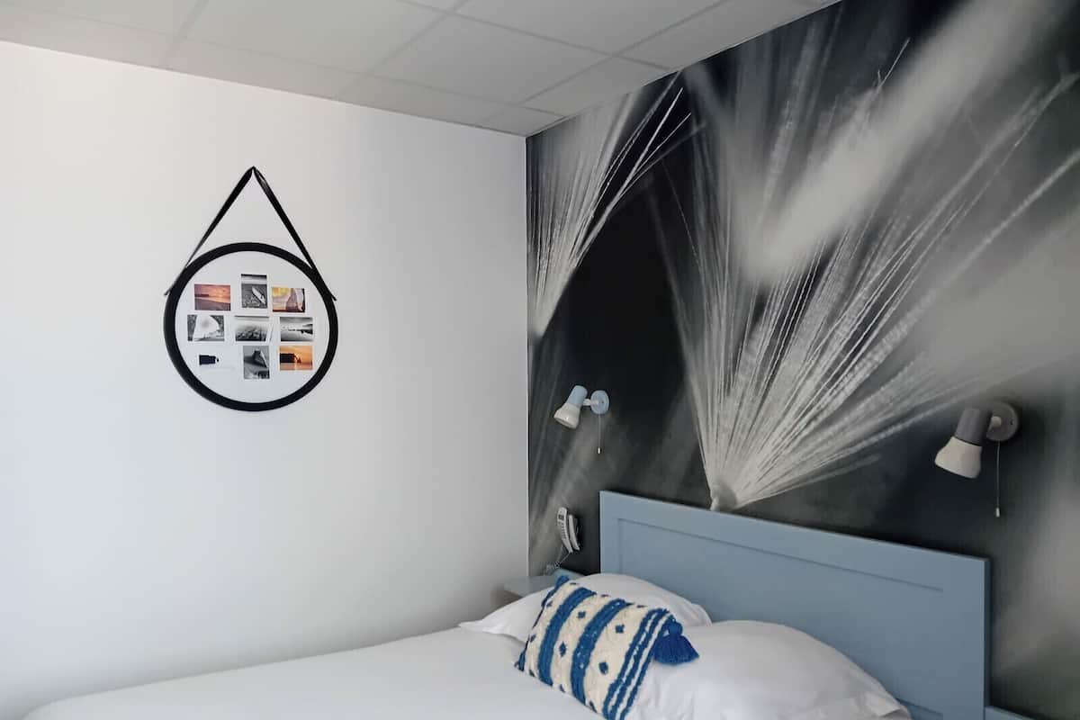 A bedroom with a bed, a wall-mounted light fixture, and a wall art piece.