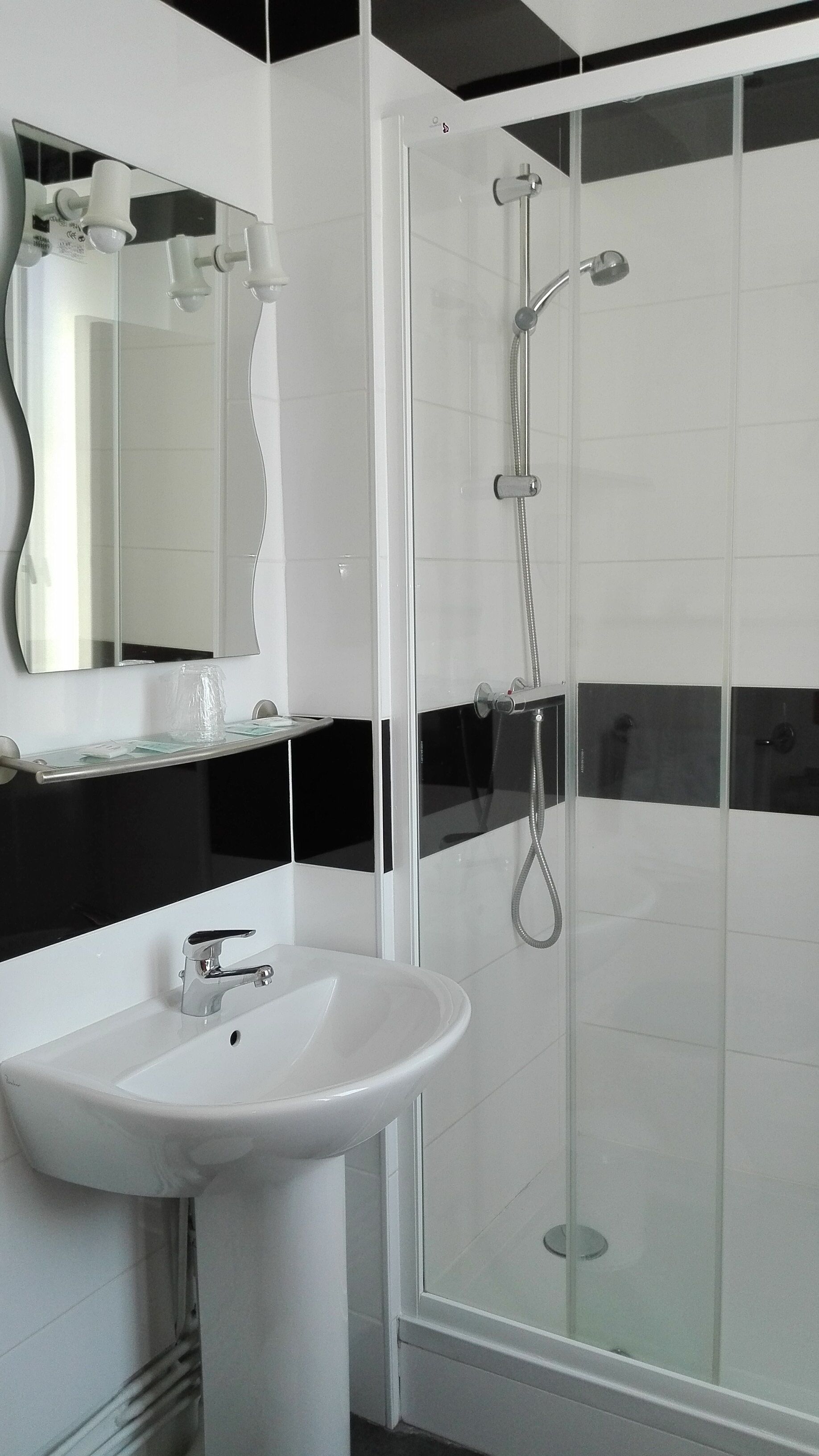 A bathroom with a white sink, a mirror, and a glass-enclosed shower.