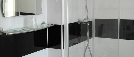A bathroom with a white sink, a mirror, and a glass-enclosed shower.