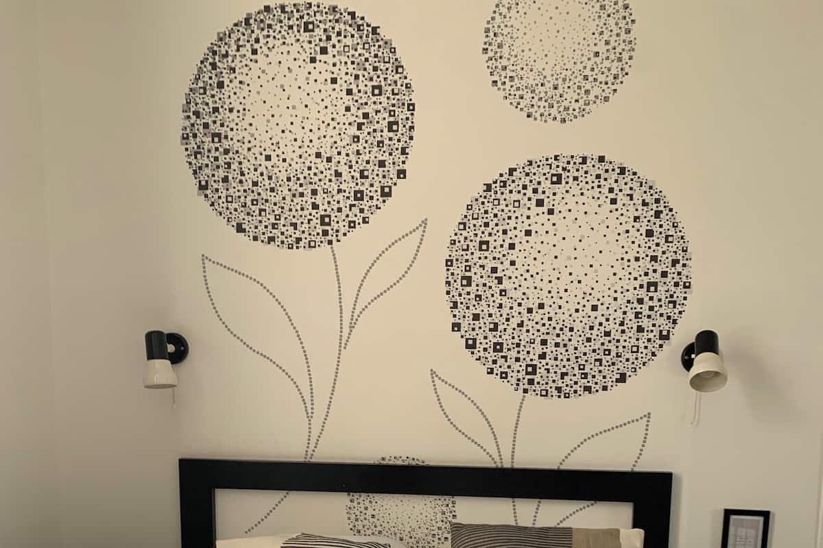 A bedroom with a bed, two bedside tables, and a wall with a decorative design.