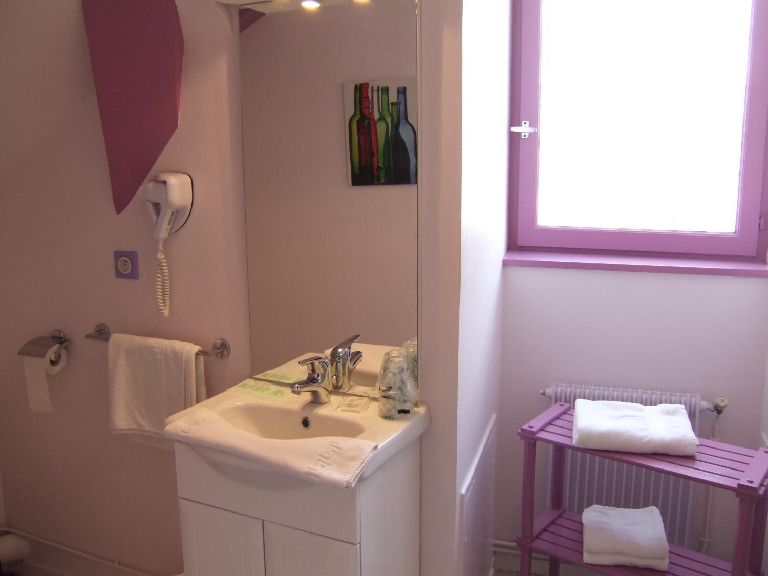 Un baño con lavamanos blanco, un espejo, un secador de pelo, toallero y una ventana con vistas.