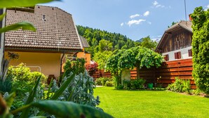 A traditional wooden house with a sloped roof, surrounded by a well-maintained garden and a clear blue sky. - Villa Nena (Kranjska Gora)
