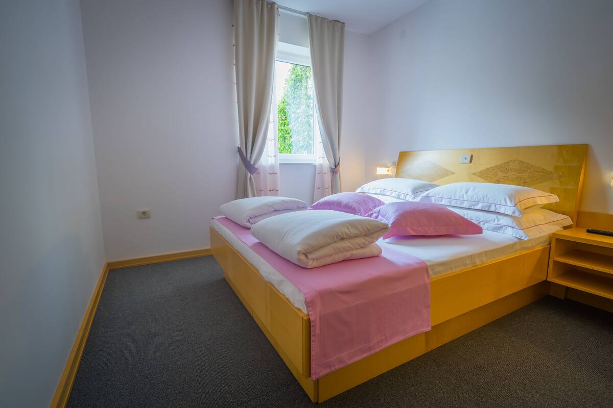 A single bed with a wooden frame, a headboard with a geometric pattern, and a bedside table with a lamp.