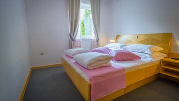 Ein Einzelbett mit Holzrahmen, ein Kopfteil mit geometrischem Muster und ein Nachttisch mit Lampe.