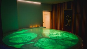 A spa room with a heated floor, a door with a monogram, and a wall with vertical wooden panels. - Villa Nena (Kranjska Gora)