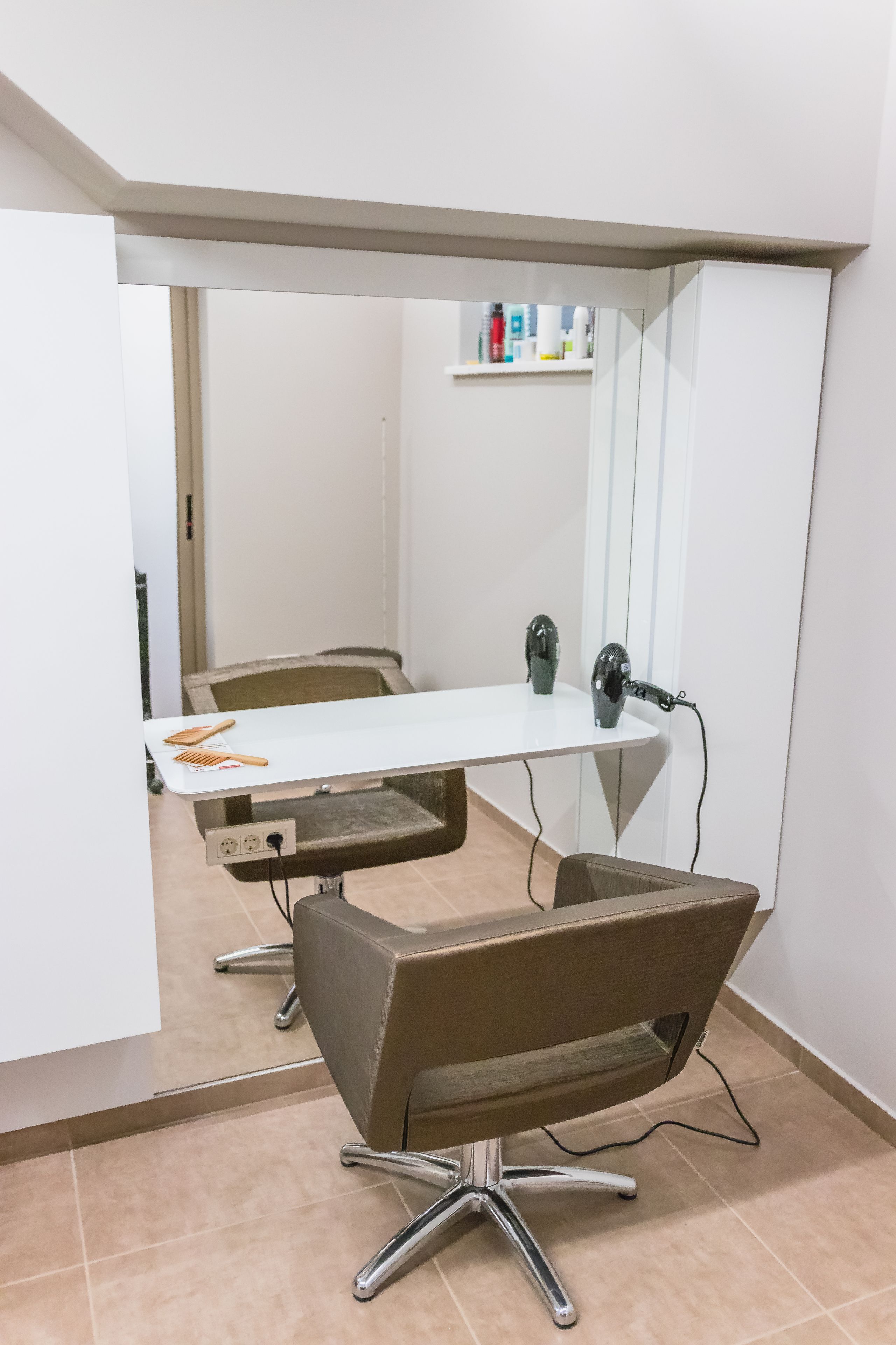 A modern office with a white desk, a brown chair, and a large mirror.