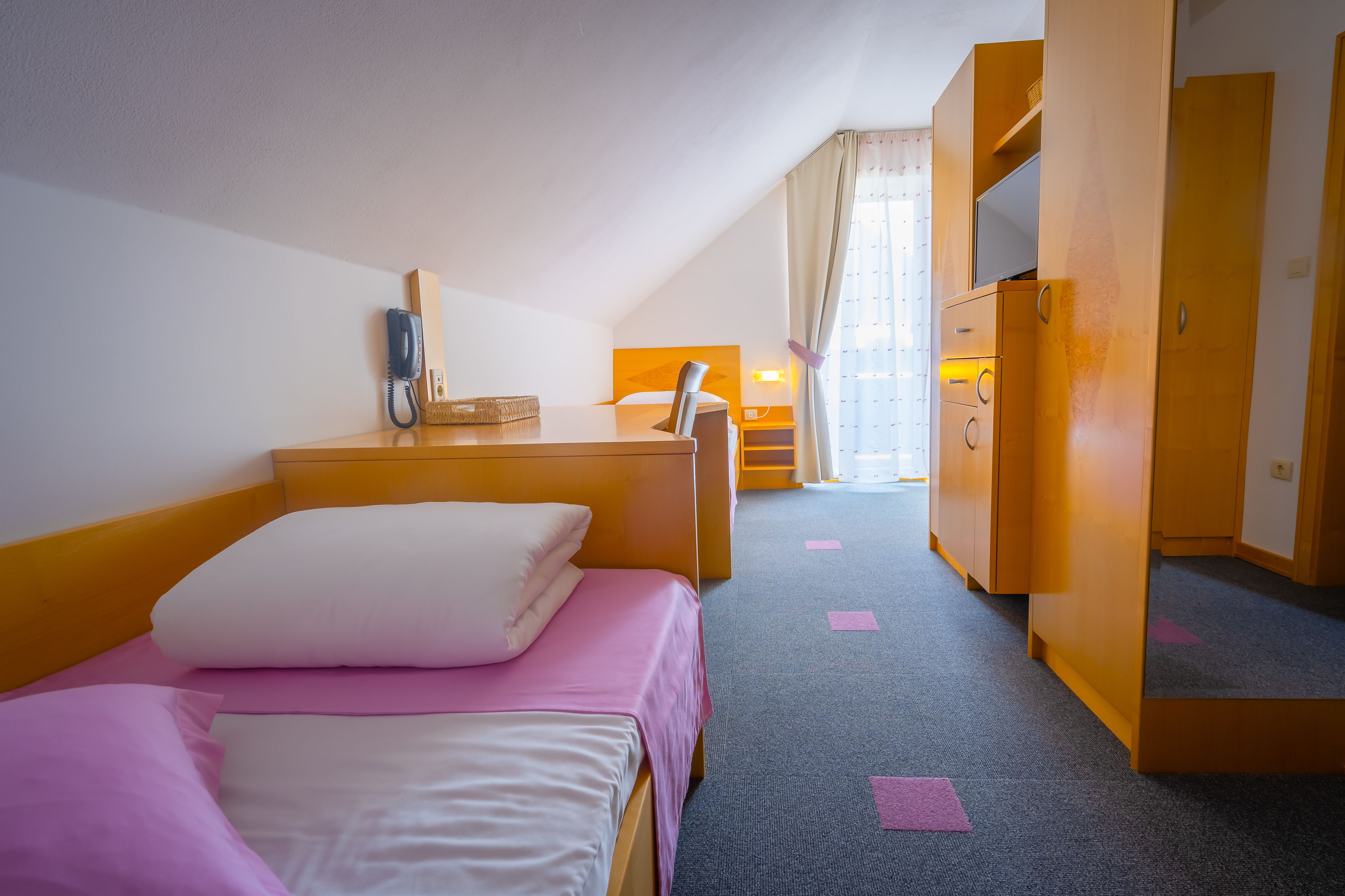 A hotel room with a bed, bedside table, lamp, and wardrobe.