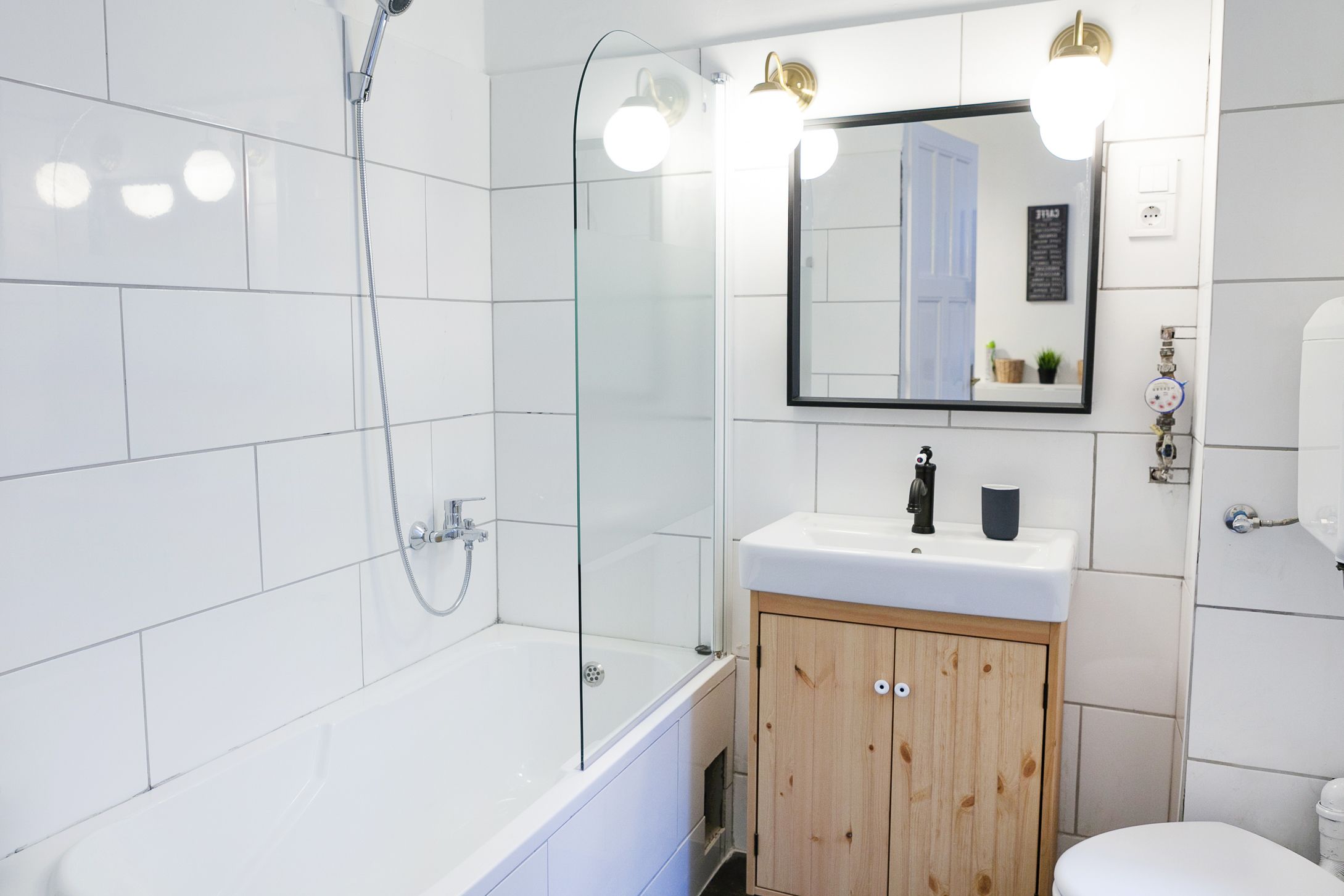 A modern bathroom with a glass-enclosed shower, a white sink, and a wooden cabinet.
