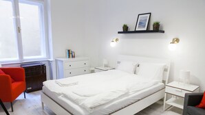 A modern bedroom with a large bed, bedside tables, a desk, and a chair.