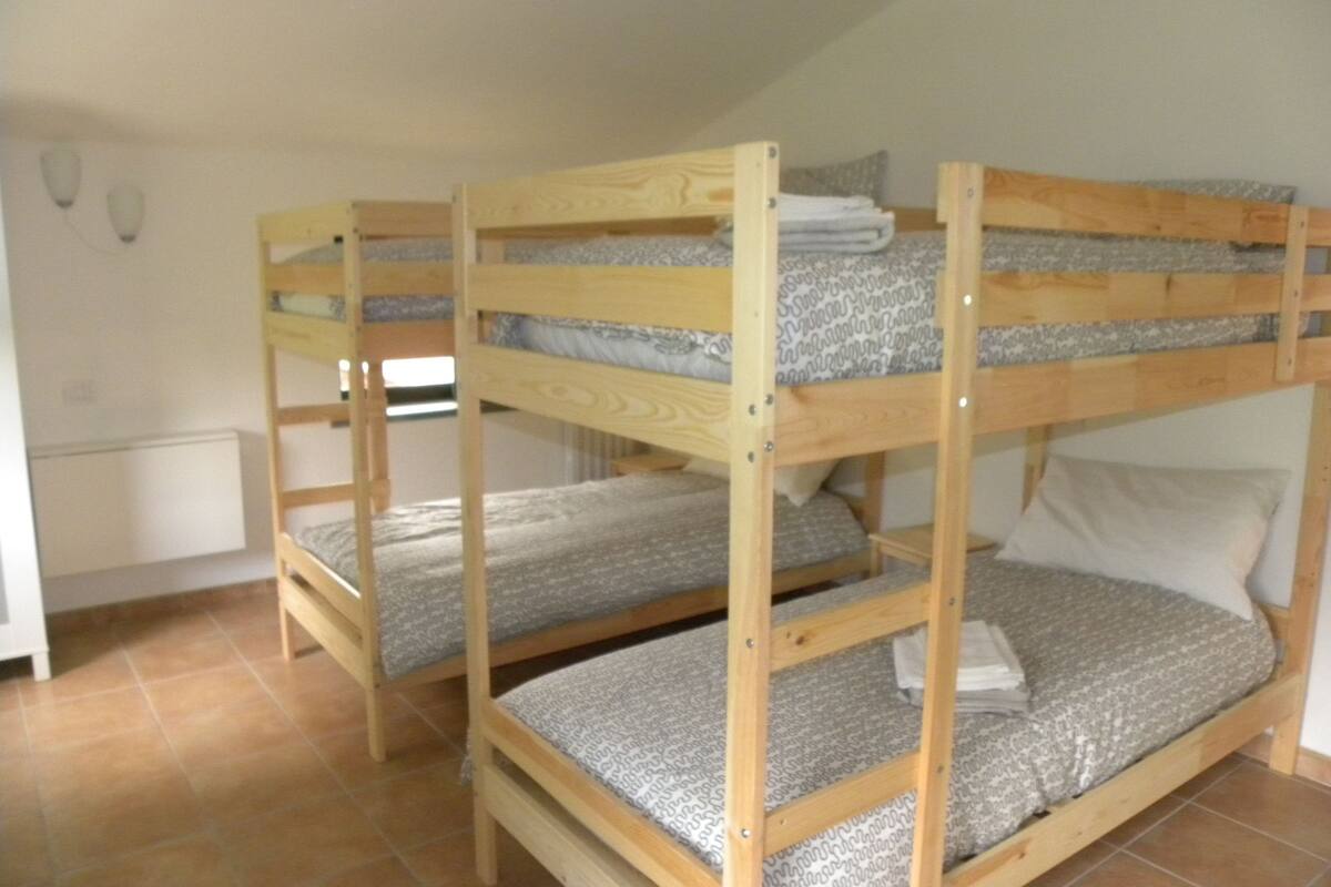 Una habitación con tres literas, un radiador y una ventana.