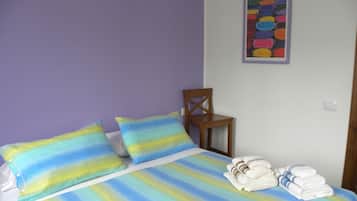 Un letto con biancheria a righe, una sedia di legno e una pila di asciugamani.