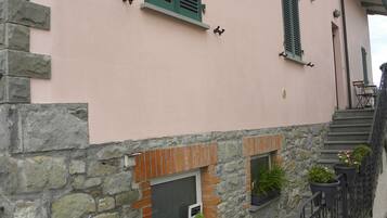 Ein Gebäude mit Steinmauern, einem Kamin aus Ziegeln und grünen Fensterläden.