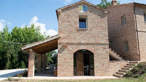 Un edificio de piedra con un porche de madera, una escalera y una puerta.