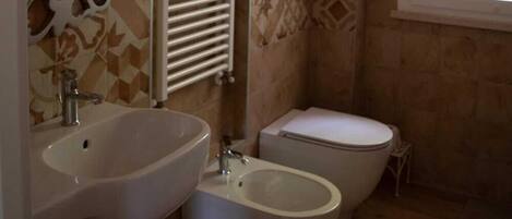 A bathroom with a sink, bidet, and toilet.