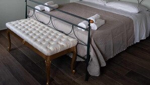 Un dormitorio con una cama, un banco, un espejo y una lámpara colgante.