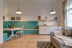 A compact kitchen with white cabinets, a dining table with chairs, and pendant lighting. - Highlight Ernesto II (Budapest)