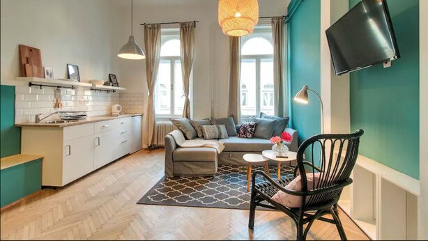 A compact living space with a kitchenette, a sofa, a dining table, and a TV mounted on the wall. - Highlight Ernesto II (Budapest)