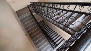Una escalera con barandilla de hierro forjado negro y pared color crema.