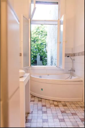 Estudio urbano, 1 cama matrimonial y sofá cama | Baño | Tina, tina de hidromasaje, toallas, jabón
