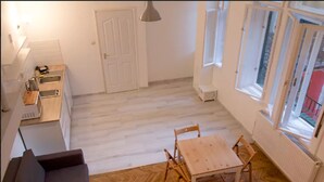 A compact living space with a kitchenette, a dining area with a table and chairs, and a sofa. - Incredible Ernesto I (Budapest)