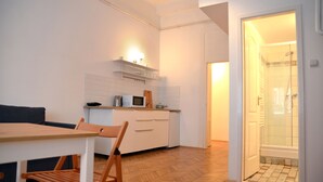 A compact kitchen with white cabinets, a microwave, and a wooden dining table with chairs. - Incredible Ernesto II (Budapest)