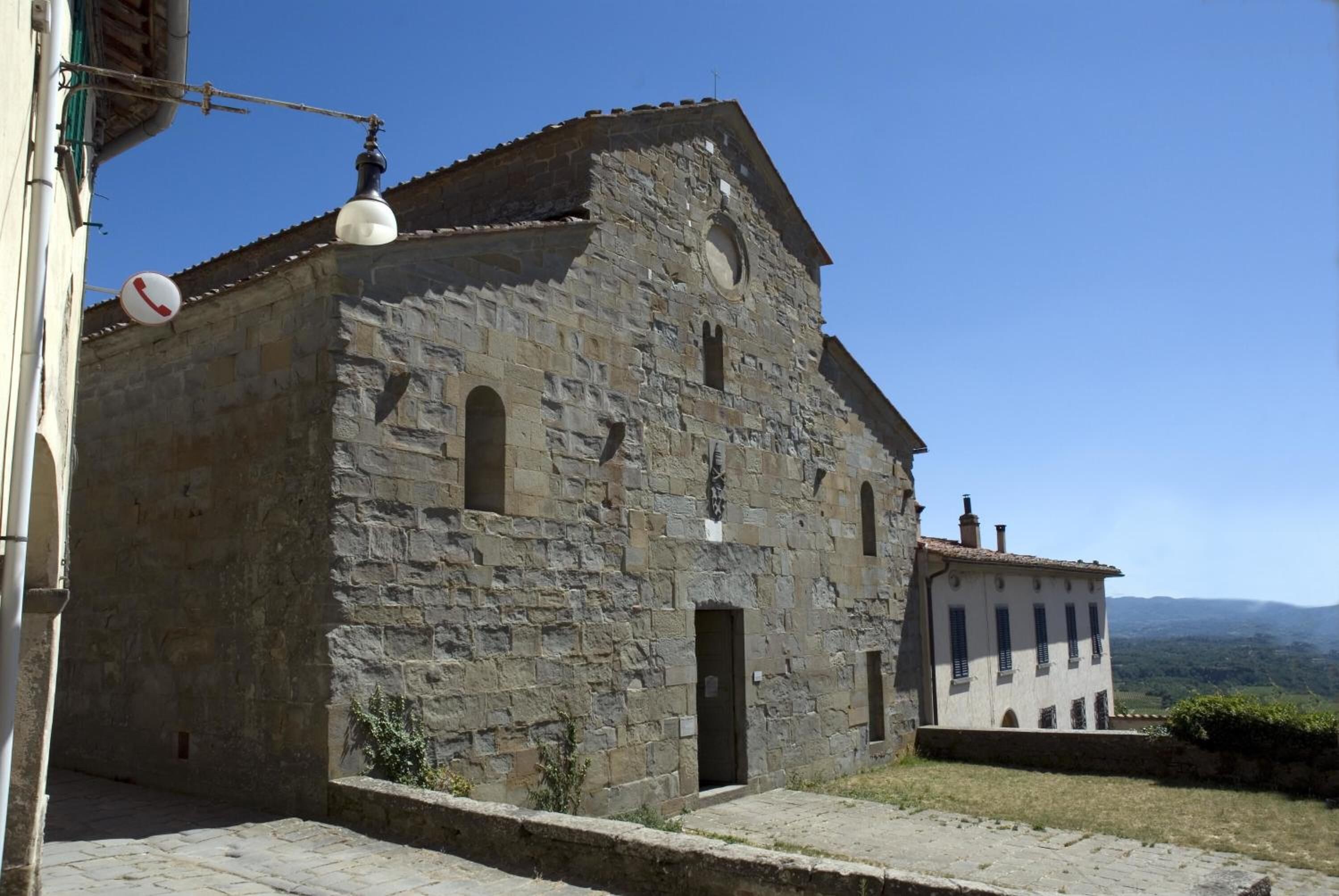 Un bâtiment en pierre doté d’un clocher, de fenêtres en arc de cercle et d’une petite porte.