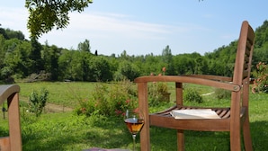 A wooden chair with a book and a glass of wine on a wooden stump in a lush green field. - A'Loro B&B (Terranuova Bracciolini)