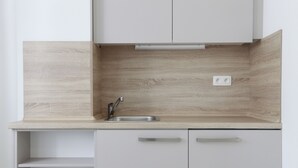 Een keuken met een licht houten spatwand, een roestvrijstalen spoelbak en witte kastjes.