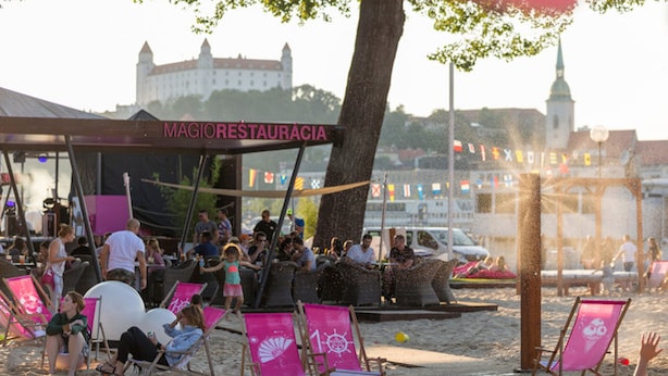 Een restaurant aan het strand met terras en uitzicht op een kasteel.