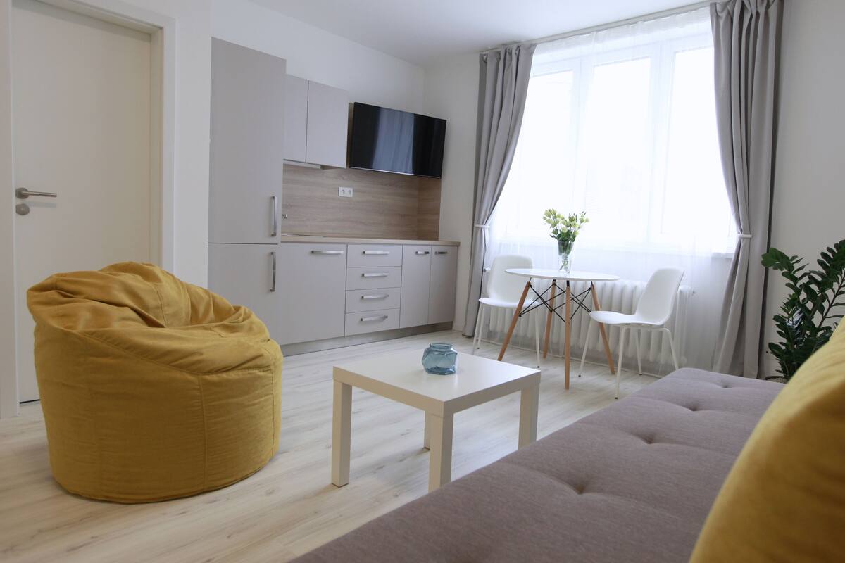 Ein modernes Wohnzimmer mit einer Couch, einem Sitzsack, einem Couchtisch und einem Essbereich mit Stühlen und einem kleinen Tisch.