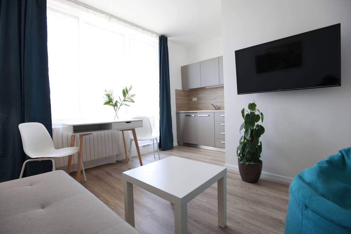 Ein modernes Wohnzimmer mit einem weißen Sofa, einem kleinen weißen Tisch und einer Topfpflanze.