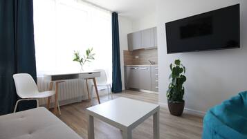 A modern living room with a white sofa, a small white table, and a potted plant.