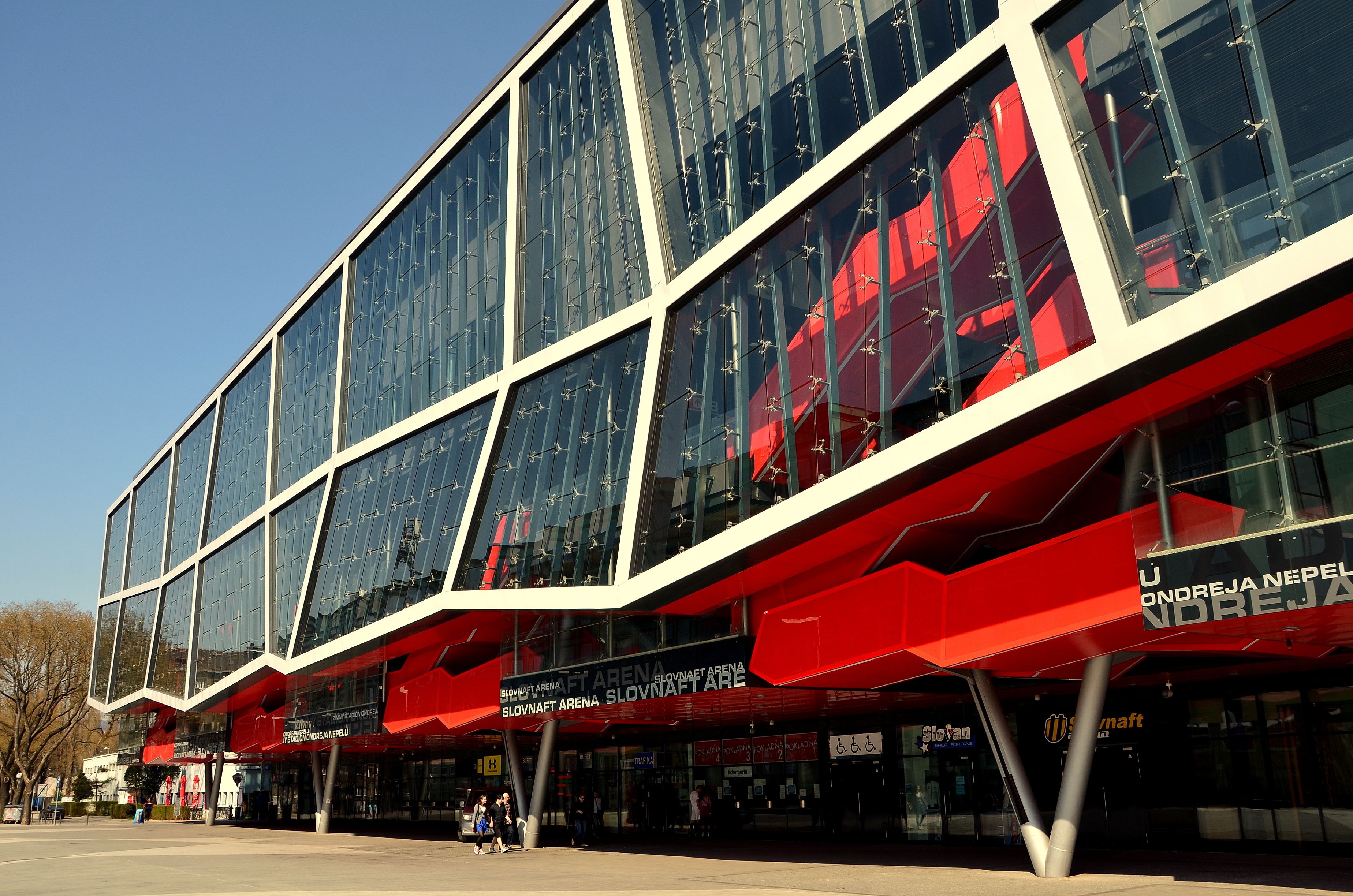 A modern building with large glass windows and red structural elements.
