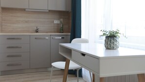 Een moderne keuken met een wit aanrecht, grijze kastjes en een witte stoel.