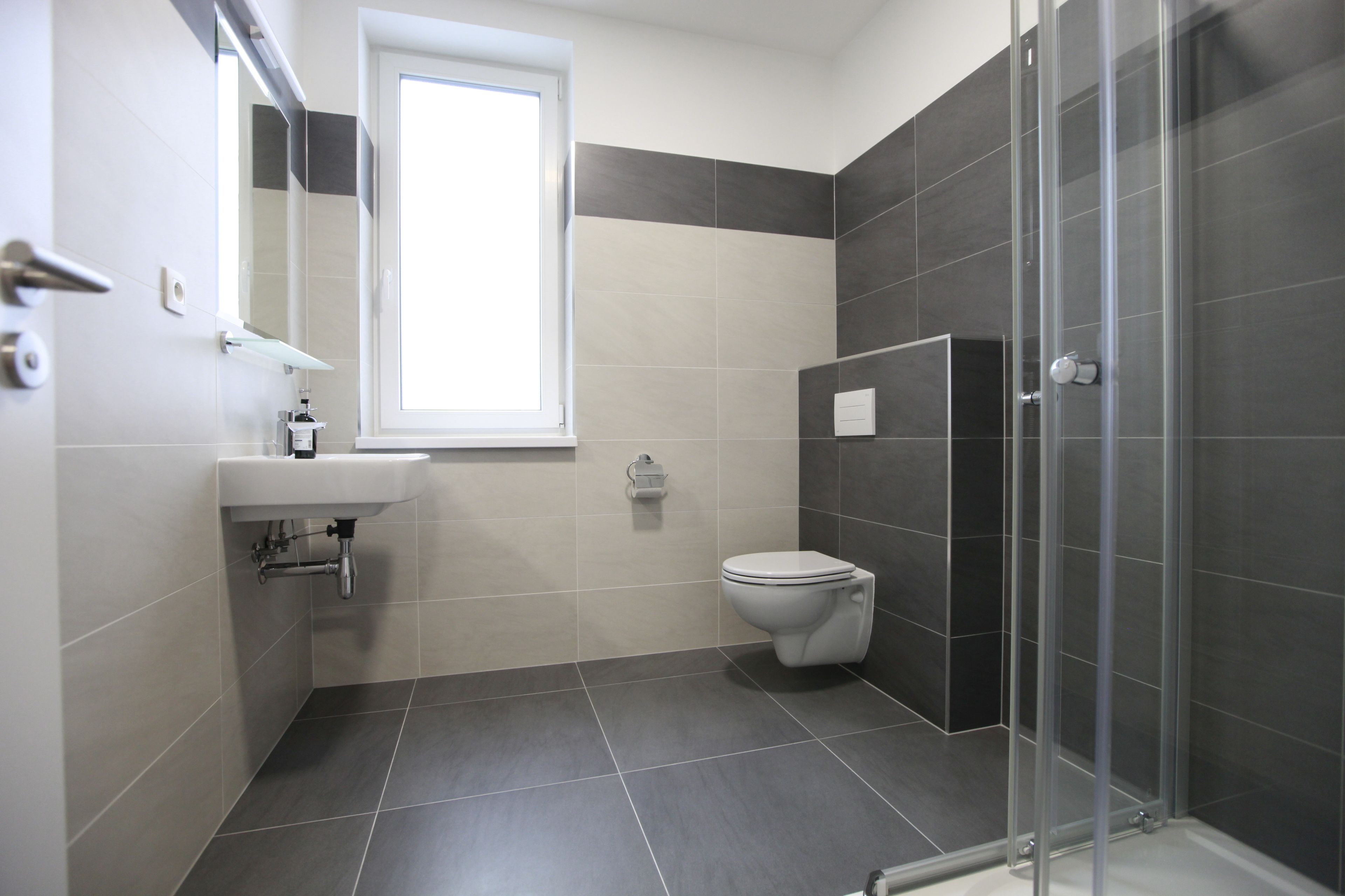 A modern bathroom with a toilet, sink, and shower.