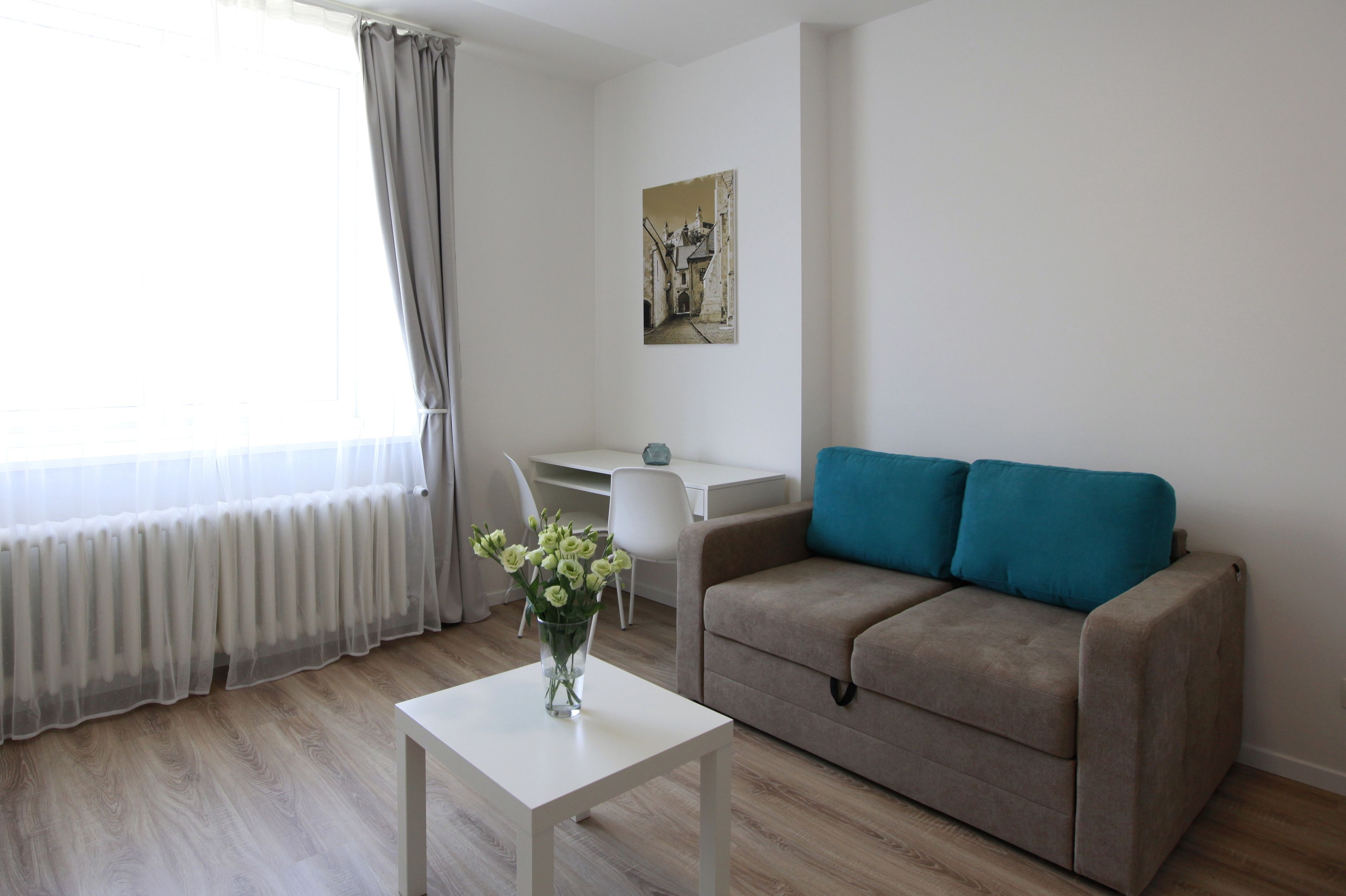 Un salón moderno con un sofá beige, una mesa de centro blanca y un cuadro en la pared.