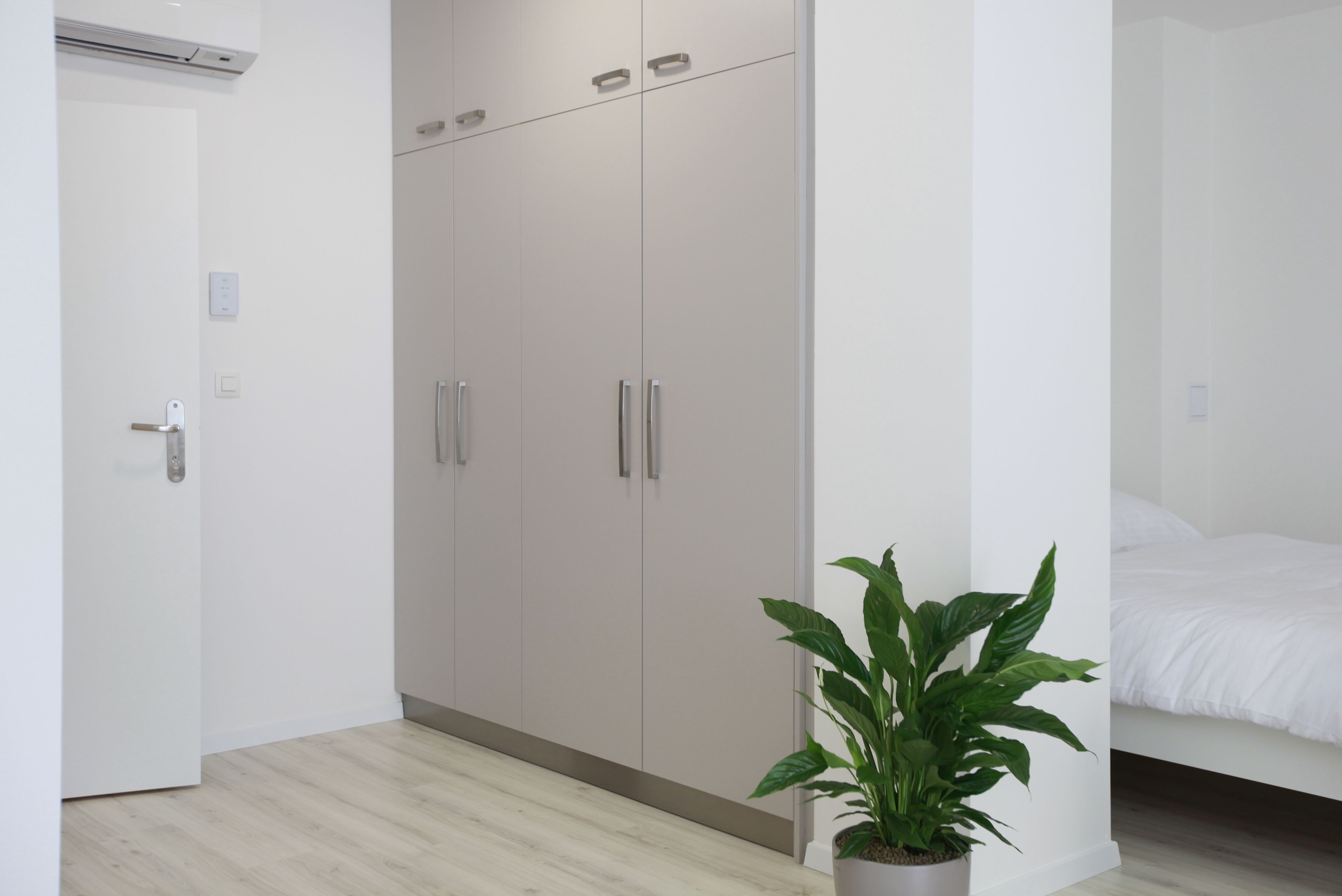 Une chambre à coucher moderne avec un lit, une armoire et une plante en pot.